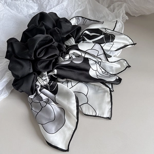 Detail of elegant black and white silk scrunchie with floral rose ribbon streamers