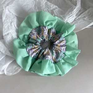 Detailed close-up of double-layered mint green floral scrunchie with Hand Made label tag