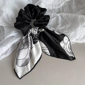 Detail showing elegant black and white camellia pattern on satin ribbon hair scrunchie