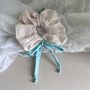 Gros plan d'un chouchou rayé rose avec un nœud en ruban de soie bleu sur papier