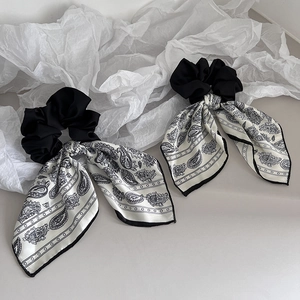 Close-up of black and white paisley silk-textured scrunchies with long bow ribbons