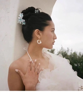 Détail de la pince à cheveux fleur nacrée et boucles d'oreilles perles sur un mannequin