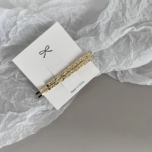 Gros plan de barrettes dorées à texture de lave sur une carte de marque blanche
