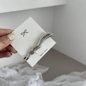 Detailed view of silver wavy alloy hair clips with polished metallic mirror finish