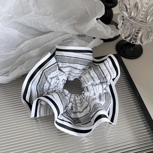 Retro striped fabric oversized scrunchie with monochrome geometric pattern on glass tray