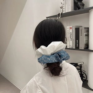 Détail d'un chouchou en tissu bleu et blanc porté en queue de cheval, style ballet chic