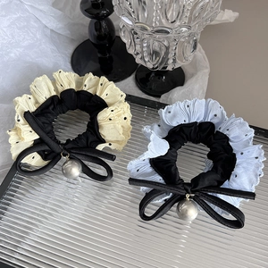 Polka dot mesh hair scrunchies with black bow and bead charm detail on glass tray