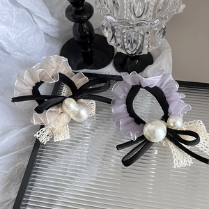 Détail de chouchous en dentelle avec perles et nœuds en velours sur plateau