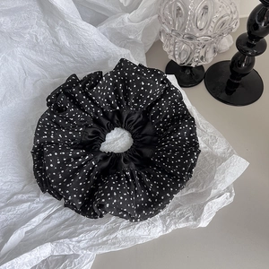 Macro shot of oversized black chiffon hair scrunchie with classic white polka dot pattern