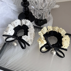 Close-up of polka dot chiffon hair scrunchies with black bows and pearl charms