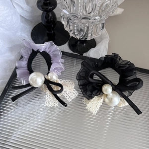 Détail de chouchou en dentelle avec mousseline violette, nœud noir et perles blanches