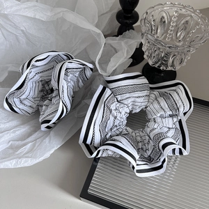 Detail of black and white striped scrunchies with chain print on pleated fabric
