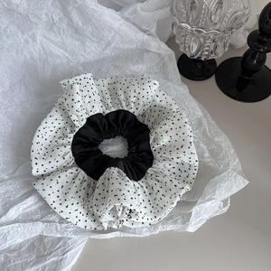 Detail shot of white chiffon scrunchie with black polka dots on artistic paper