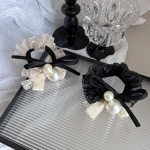 Détail de chouchous en dentelle avec plis en organza, nœuds noirs et perles nacrées