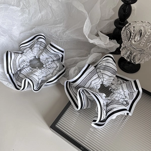 Detail showing two black and white striped hair scrunchies with chain pattern and fabric texture