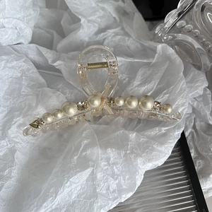 Detail of elegant pearl hair claw with crystal rhinestones and beige ribbon bow ornament