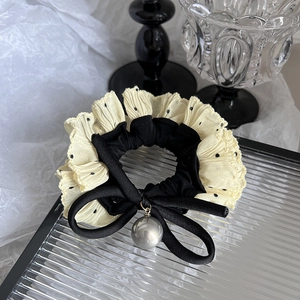 Detail of polka dot ruffle hair scrunchie with a pearl charm on a glass tray