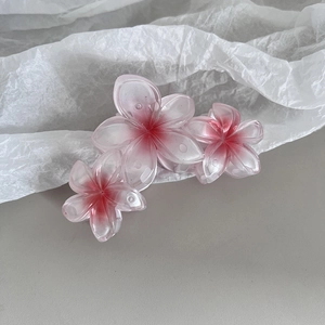 Détail de la pince à cheveux avec fleurs de frangipanier à dégradé rose en résine translucide