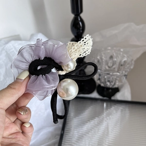 Détail d'un chouchou en organza violet avec dentelle et perles blanches décoratives