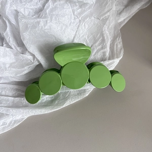 Detailed view of glossy bright green hair claw clip with unique circular design elements