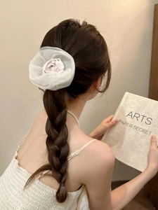 Détail d'un grand chouchou fleur en organza blanc sur une coiffure avec tresse