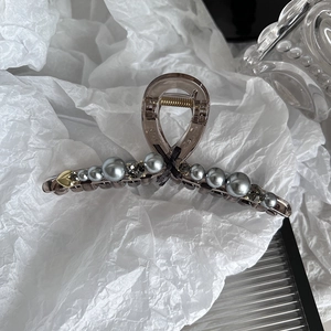 Detail of large brown hair claw clip with grey pearls, black crystals, and gold heart