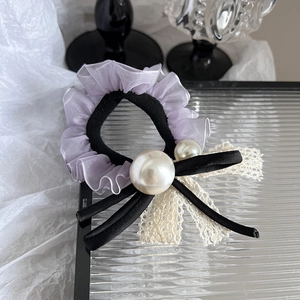 Détail d'un chouchou en dentelle organza lavande avec perles et nœud satiné
