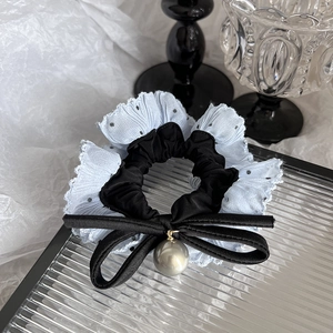 Detail of satin hair scrunchie with polka dot lace trim and grey pearl bow charm
