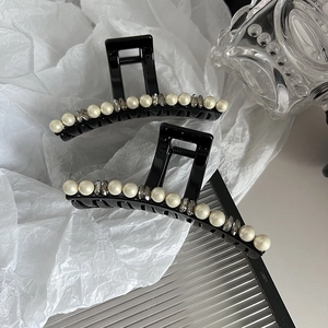 Dettaglio di un elegante fermaglio per capelli nero con perle intarsiate e cristalli grigi
