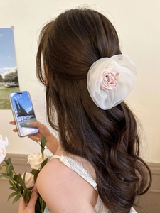 Vue détaillée d'une pince à cheveux camélia en organza blanc crème sur modèle en intérieur