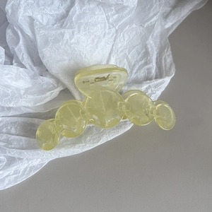 Detail view of a translucent yellow disc hair claw clip with a strong metal spring