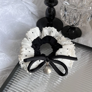 Detail of polka dot lace scrunchie with a sleek black bow and large faux pearl charm