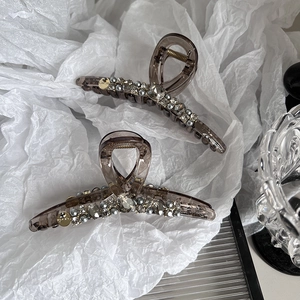 Pinces à cheveux marron foncé avec cristaux et perles sur fond de papier blanc plissé