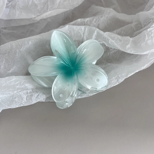 Détail d'une pince à cheveux fleur dégradé bleu sur du papier crépon blanc doux