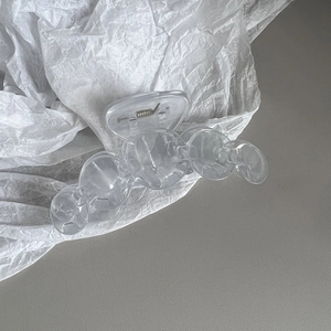Detail of a large transparent acrylic claw clip with a five-sphere design on a white background