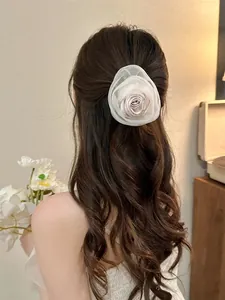 Détail d'une grande pince à cheveux fleur en organza blanc sur des cheveux ondulés