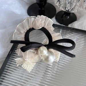 Chouchou élégant en dentelle organza avec perles et nœud en satin noir sur plateau verre