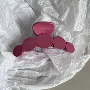 Detail shot of the vibrant rose pink resin hair claw with five geometric circular dots