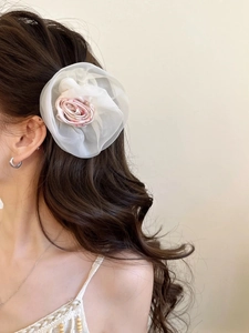 Détail d'une pince à cheveux fleurie en organza sur cheveux ondulés style été
