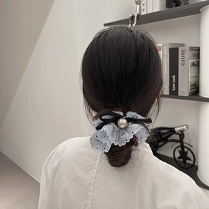 Elegant blue lace polka dot scrunchie with large pearl and black ribbon on a low bun