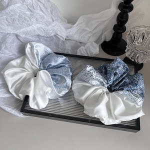 Détail de deux chouchous en satin surdimensionnés avec motif dégradé bleu et blanc