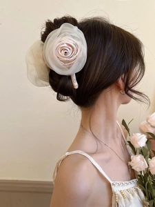 Détail d'une grande pince à cheveux en fleur d'organza portée sur une coiffure attachée