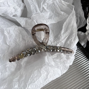 Détail d'une grande pince à cheveux avec strass et perles sur papier blanc