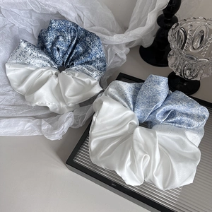 Détail de deux grands chouchous en satin bleu et blanc dans un décor de haute qualité