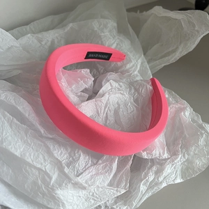 Detail of neon pink thick sponge headband featuring a black handmade textile label