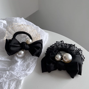 Detail view of black satin bow hair ties with polka dot lace and elegant white faux pearls