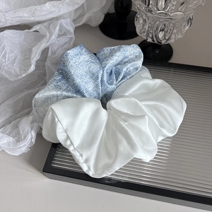 Détail de chouchous en satin bleu et blanc sur plateau avec texture soyeuse et brillante