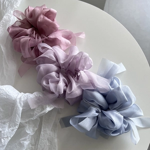 Detailed view of three chiffon scrunchies in purple and blue with soft translucent texture