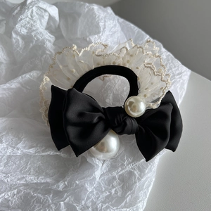 Elegant black bow hair tie featuring white pearls and beige lace on a neutral background