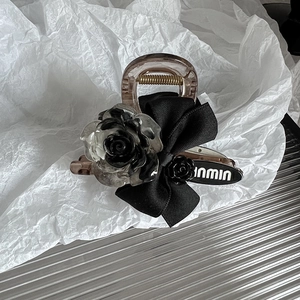 Détail d'une pince à cheveux en résine avec un nœud en tissu et une rose en dégradé